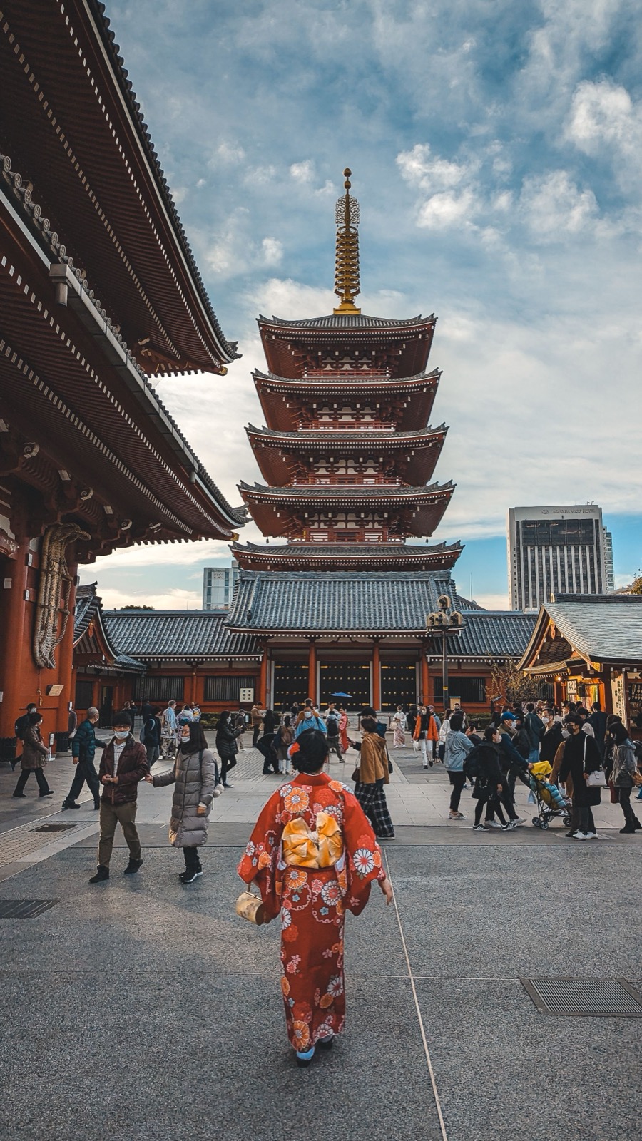 Femme en kimono marchant vers la pagode du temple Sensō-ji, à travers la foule