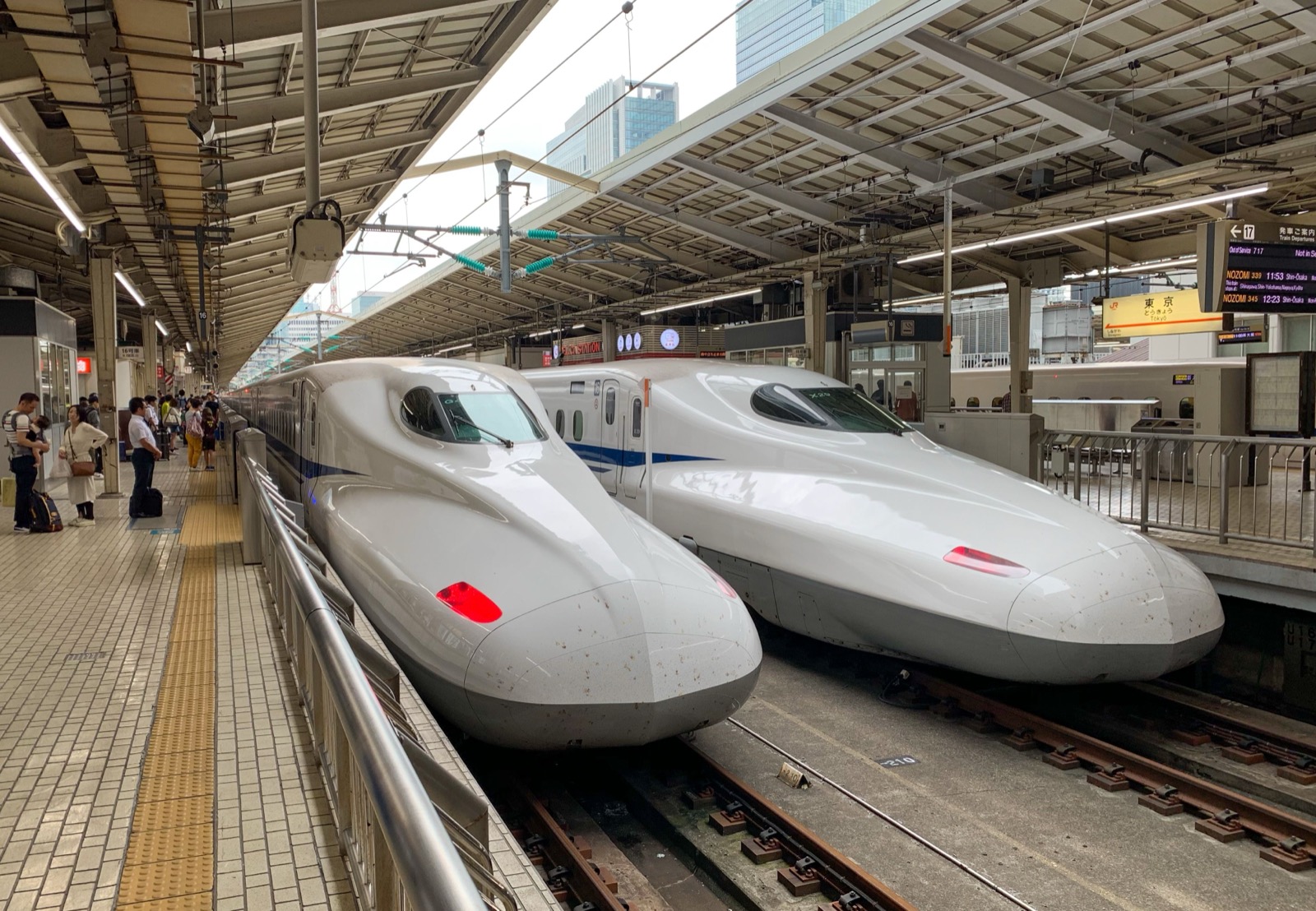 Deux Shinkansen à quai avec panneau d'annonces des départs à la gare de Tokyo