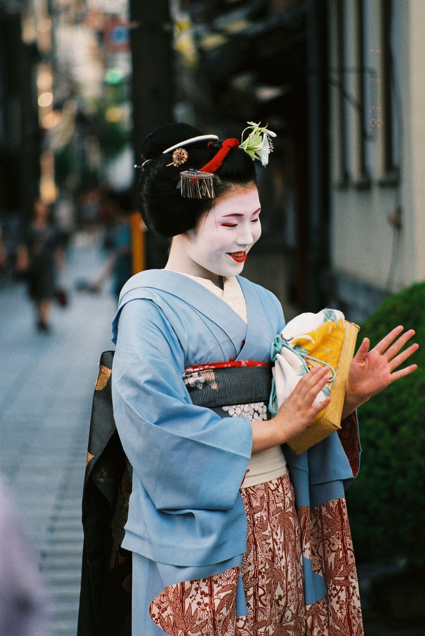 Geiko en kimono bleu clair, maquillage blanc et obi, dans une rue de Kyoto