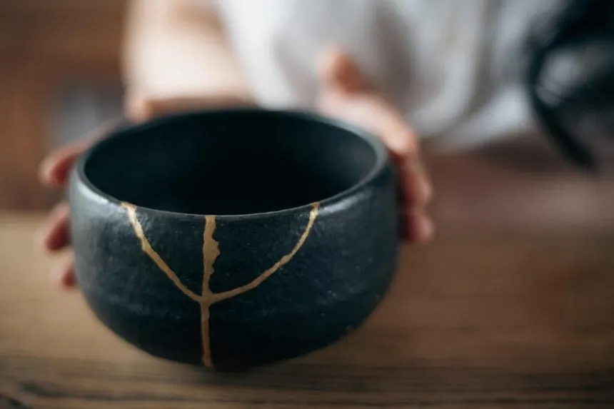 Bol en céramique noire réparé au kintsugi, la fêlure soulignée d'une ligne de laque dorée