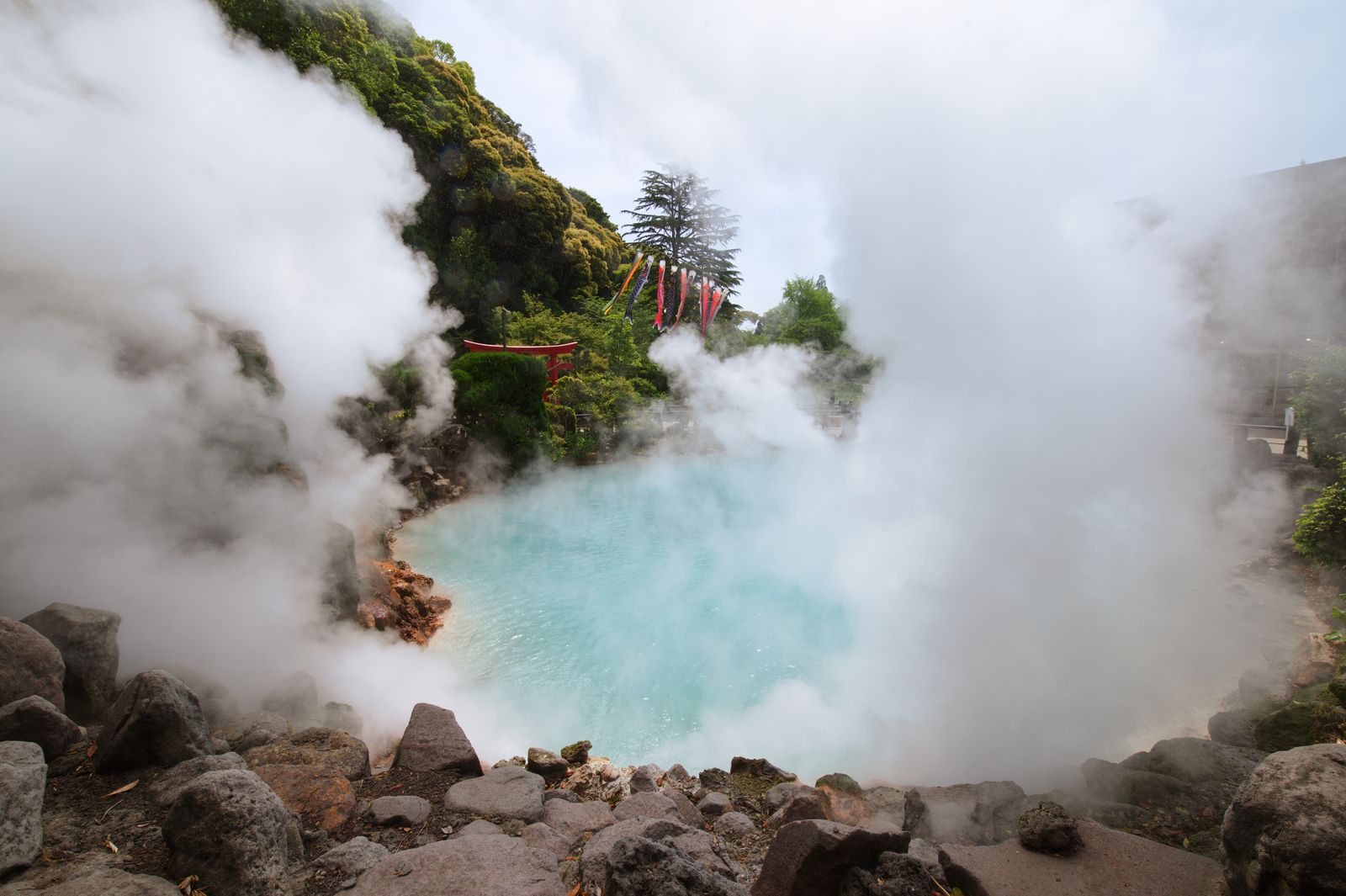 Étang géothermal turquoise fumant avec un petit torii, dans les enfers de Beppu