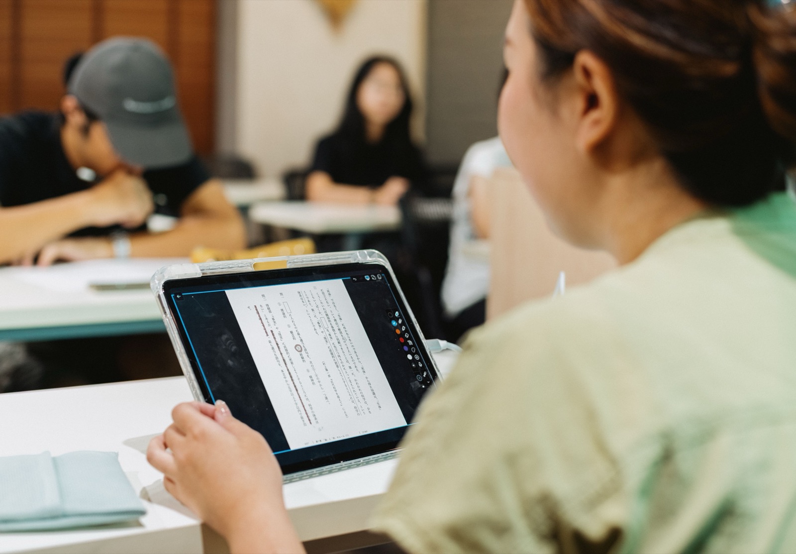 Étudiante s'exerçant sur un texte japonais en classe, sur tablette